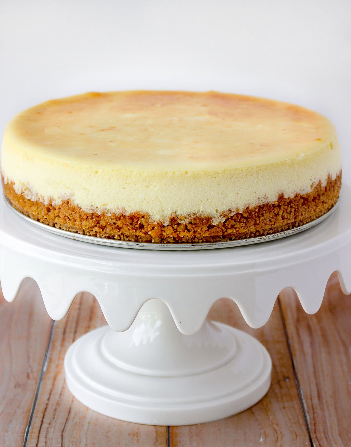 plain cheesecake recipe on white cake stand without toppings.