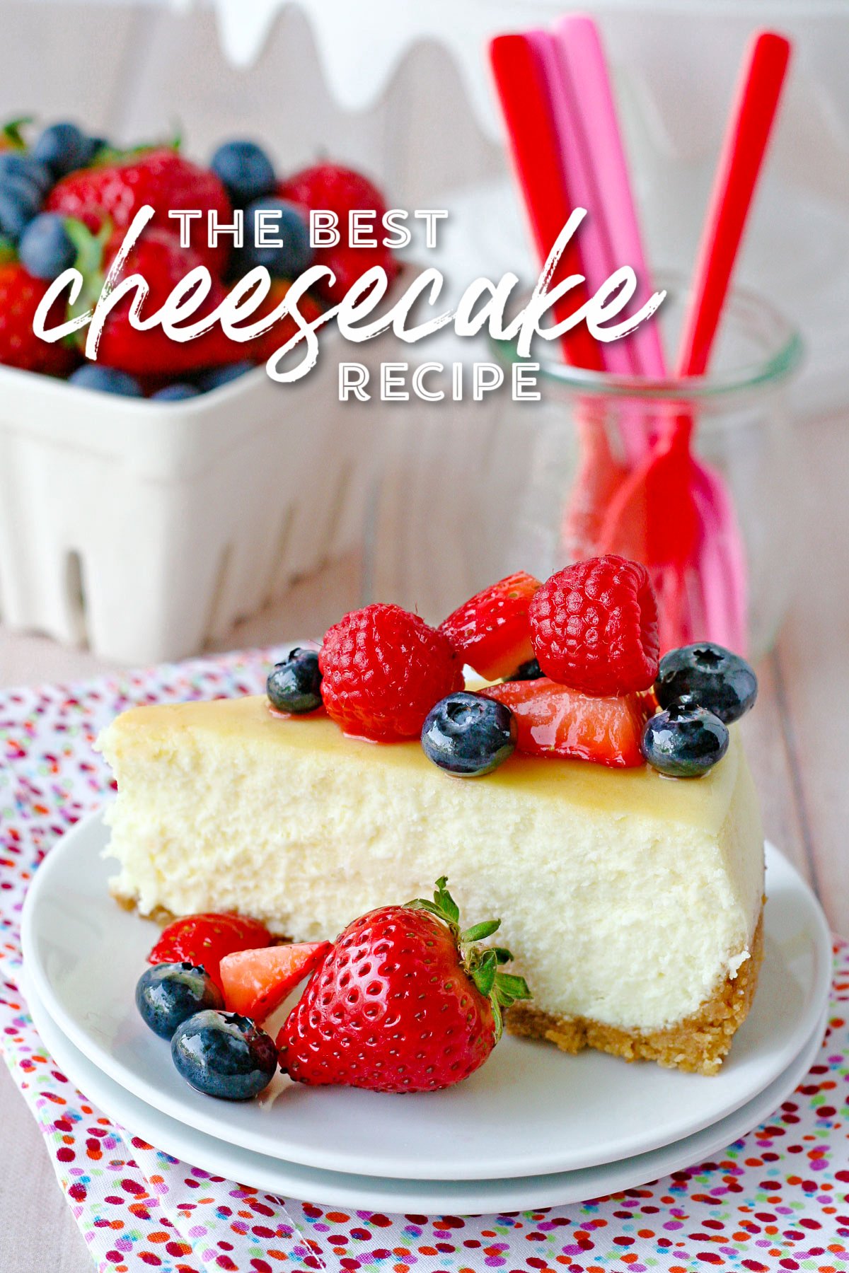 slice of cheesecake on white plate topped with fresh berries. title overlay at top of image.