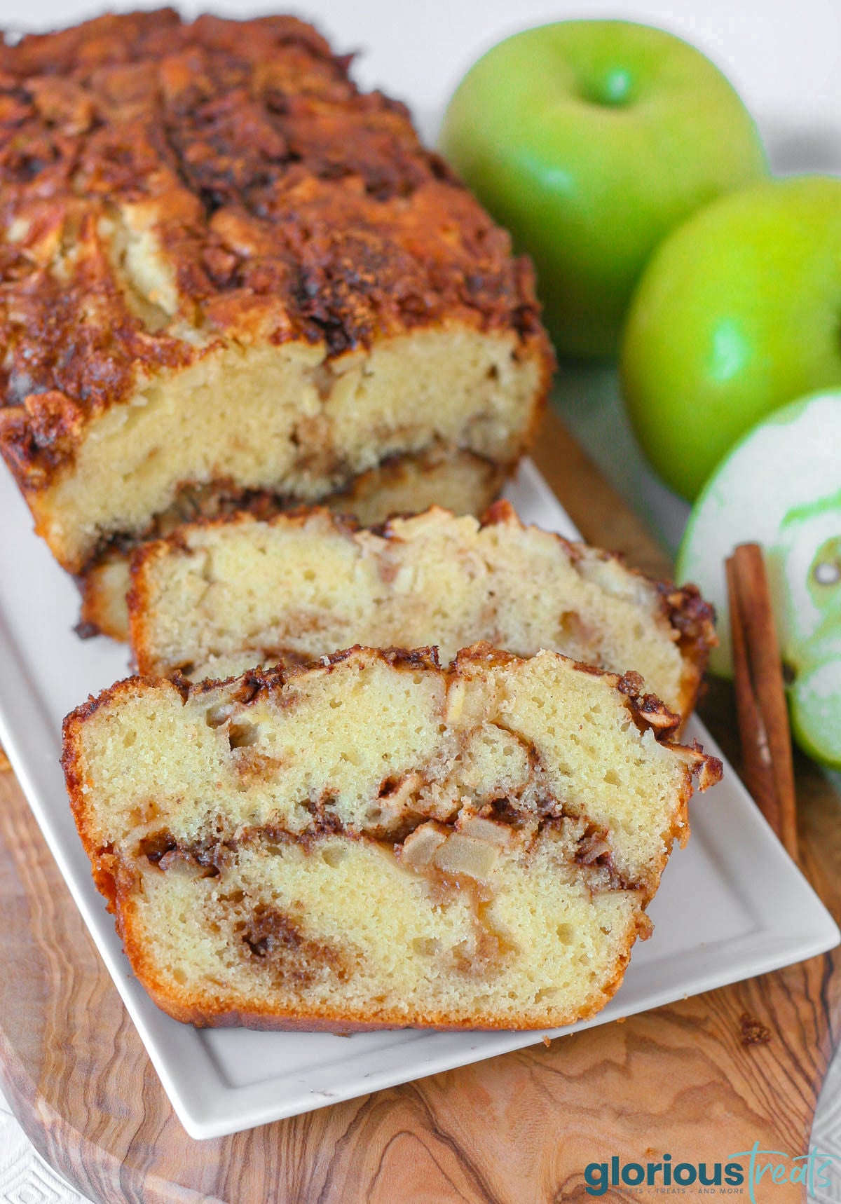 Close up look at two slices of apple bread on white serving tray with the rest of the loaf.