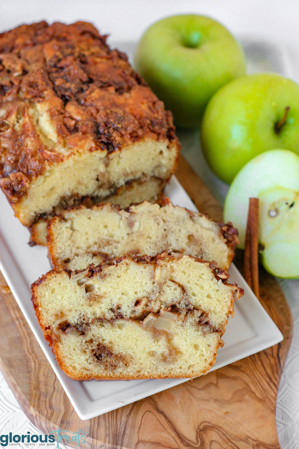 Close up look at two slices of apple cinnamon bread on white serving tray with the rest of the loaf.