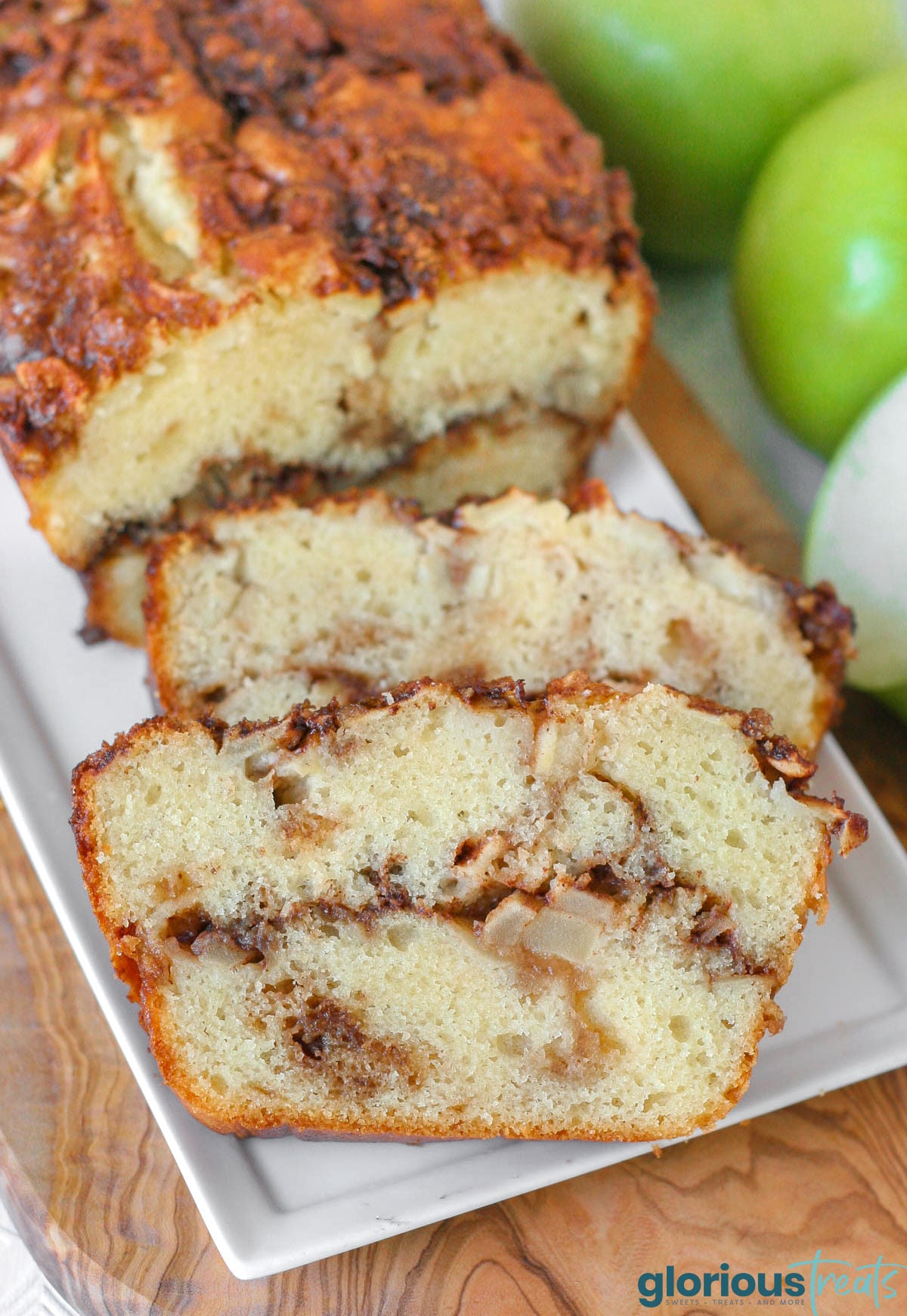 Close up look at two slices of apple cinnamon bread on white serving tray with the rest of the loaf.