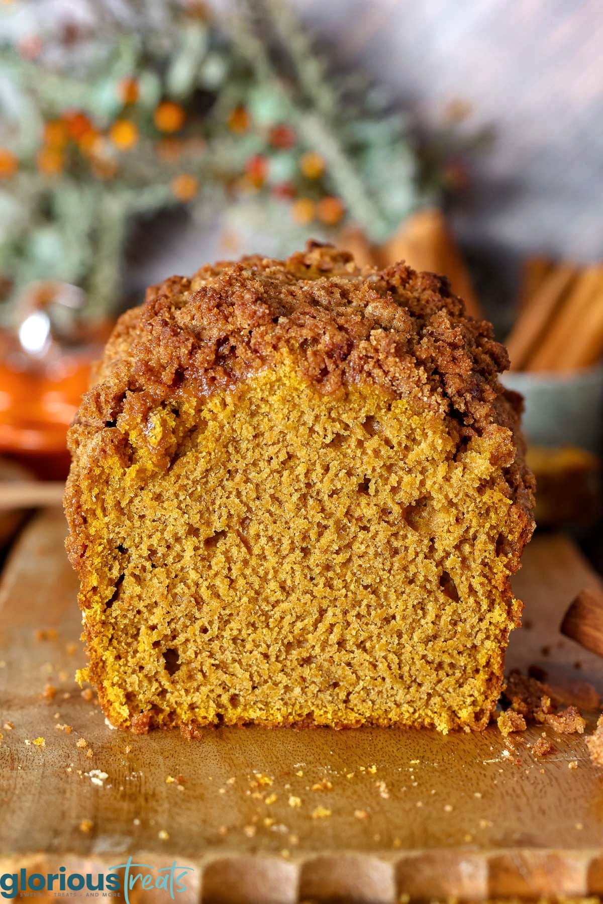 Loaf of pumpkin bread on wood board with end cut off so the moist interior is showing.