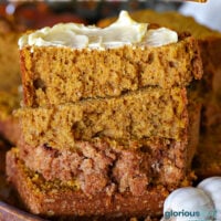 Tall graphic showing stacked slices of pumpkin bread with a cinnamon streusel topping. Top slice is buttered. A shot of the cross section of the pumpkin loaf is shown next to the title at the top of the image.