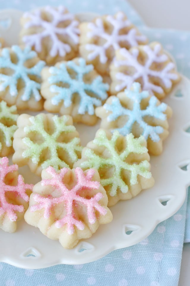 spritz cookies on white plate frosted in four pastel colors