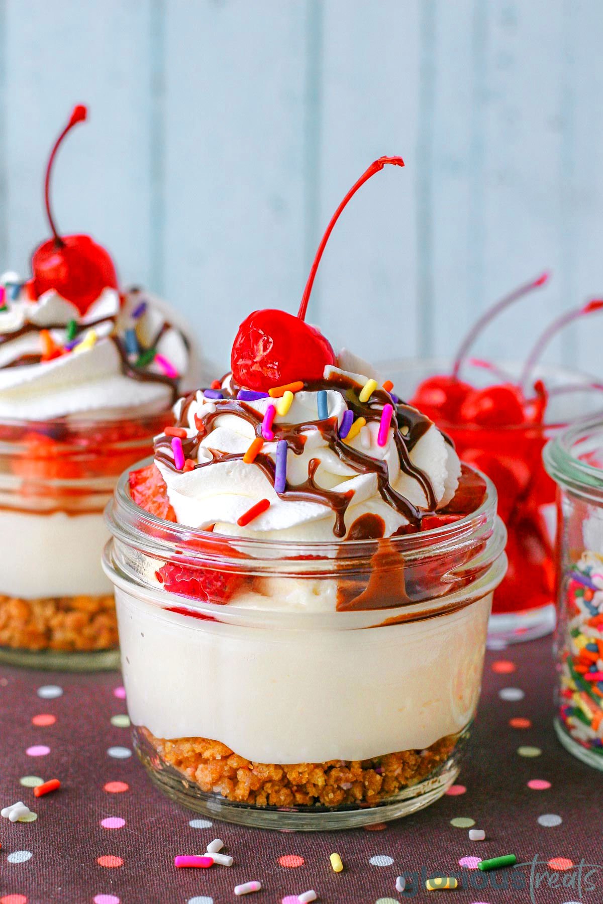 Banana split cheesecake in small jar made with no bake cheesecake, graham cracker crumble and fresh fruit toppings.