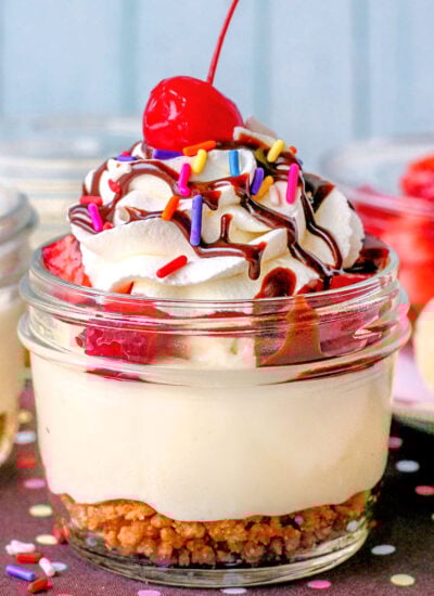 Banana split cheesecake in small jar made with no bake cheesecake, graham cracker crumble and fresh fruit toppings.