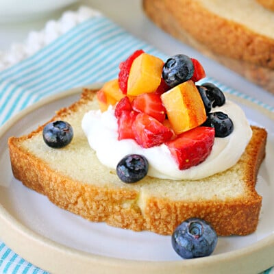 close up look at pound cake slice topped with cream and berries.