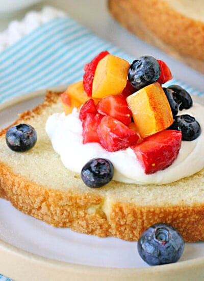 close up look at pound cake slice topped with cream and berries.