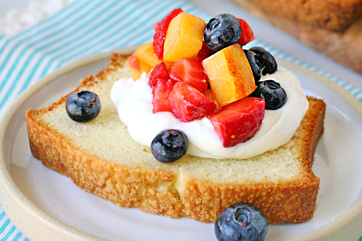 close up look at pound cake slice topped with cream and berries.