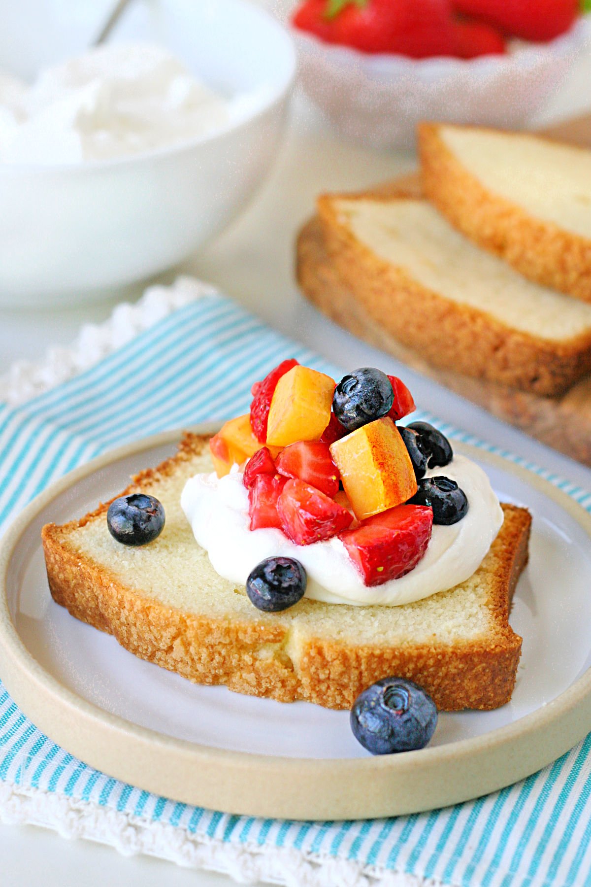 close up look at pound cake slice topped with whipped cream and fruit.