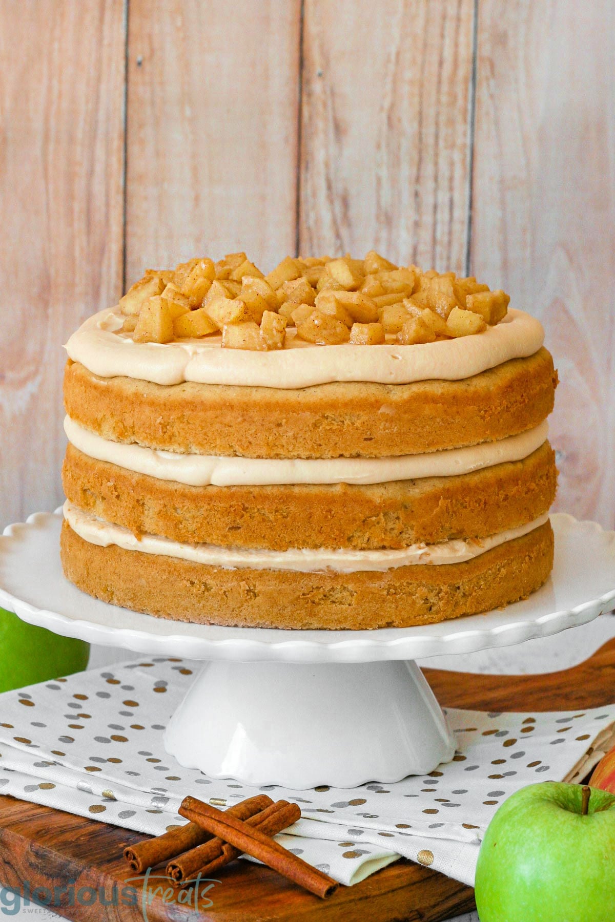 Caramel apple cake before the caramel drizzle has been added. Shown on white cake stand.