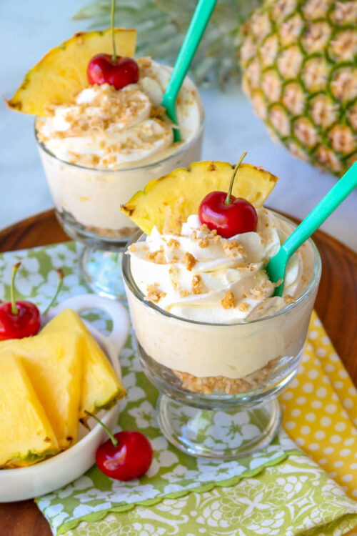Pina Colada Cheesecake Mousse in glass dishes with cherry and pineapple