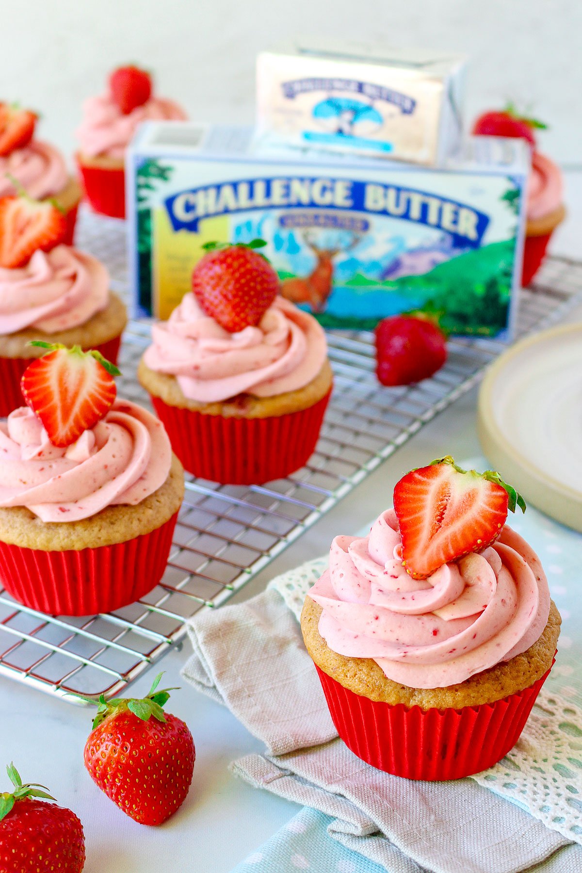 strawberry cupcakes topped with strawberry frosting with butter package in back