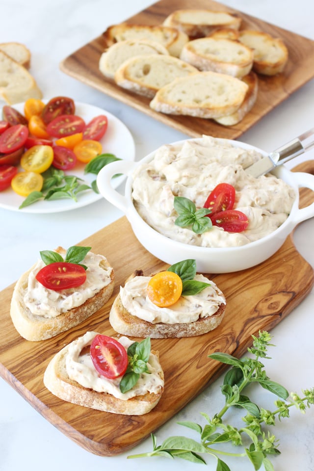 Caramelized Onion and Bacon Dip ready on wood board to serve with crostini