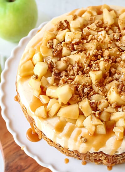 top down view caramel apple cheesecake recipe on white cake plate sitting on wood board