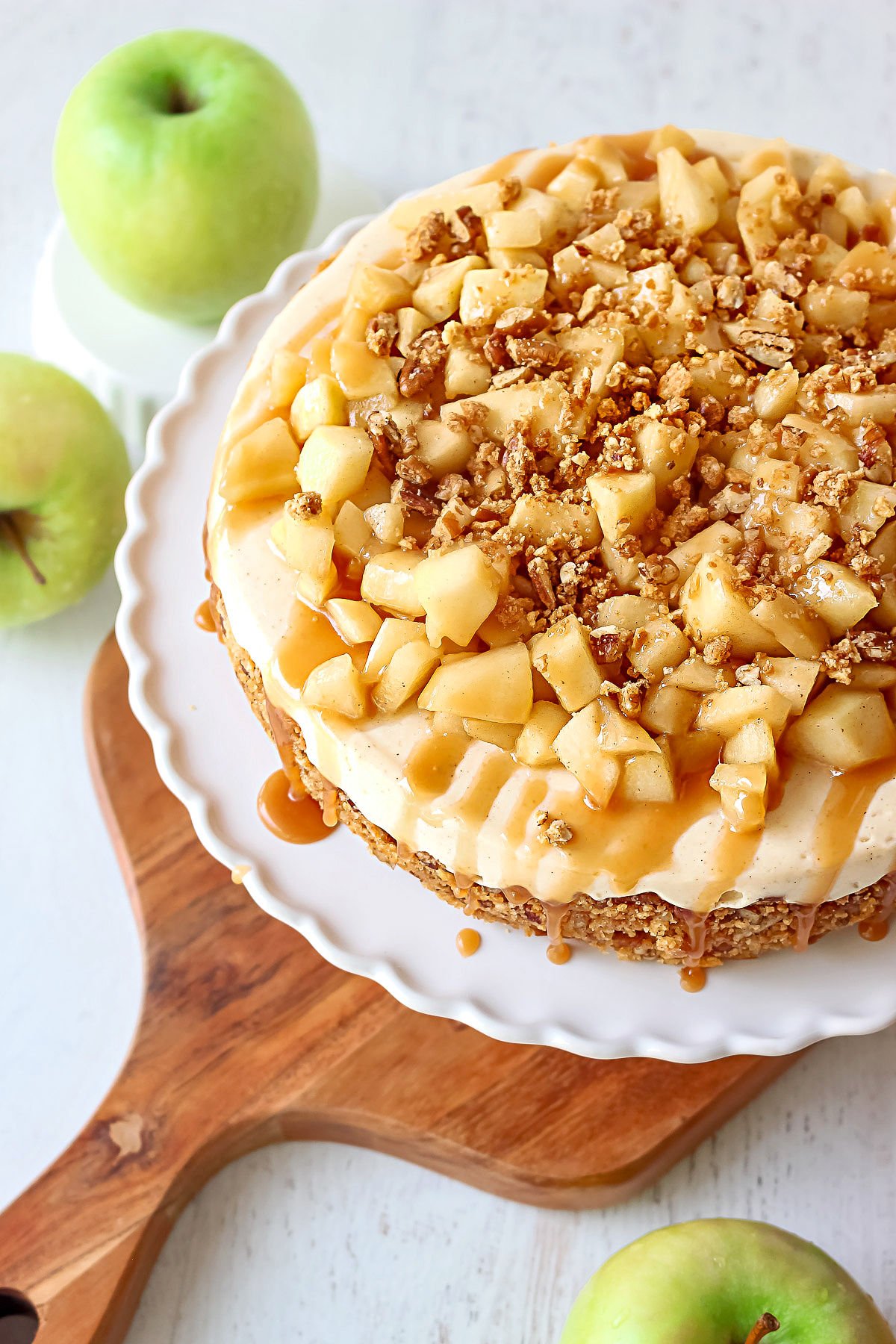 top down view caramel apple cheesecake recipe on white cake plate sitting on wood board