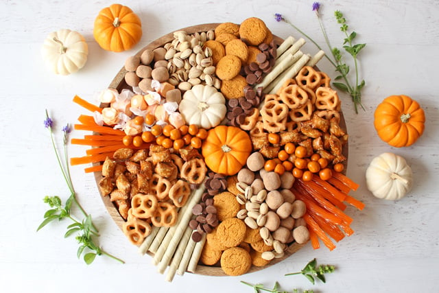 wide overhead view of charcuterie board with orange and brown trets