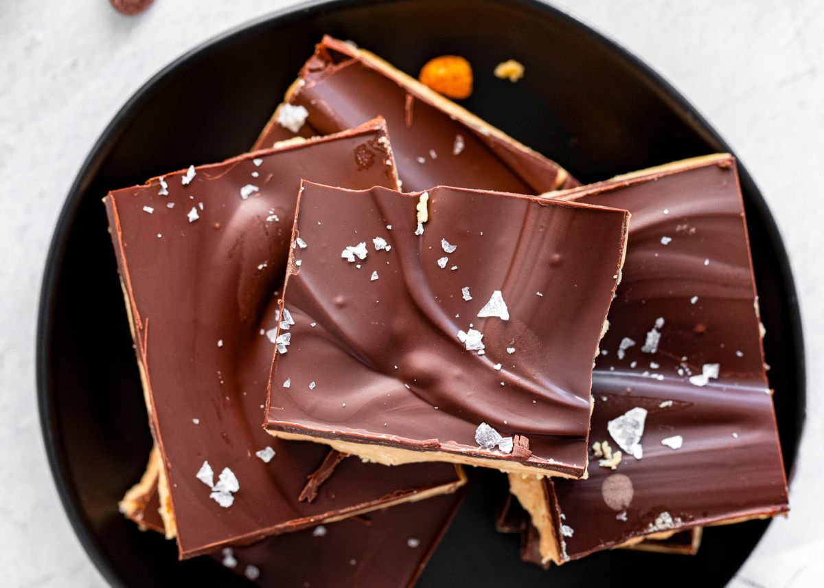 chocolate peanut butter bars topped with sea salt sitting on small black plate.