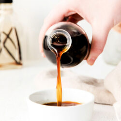 vanilla extract being poured from a bottle into a small white bowl.