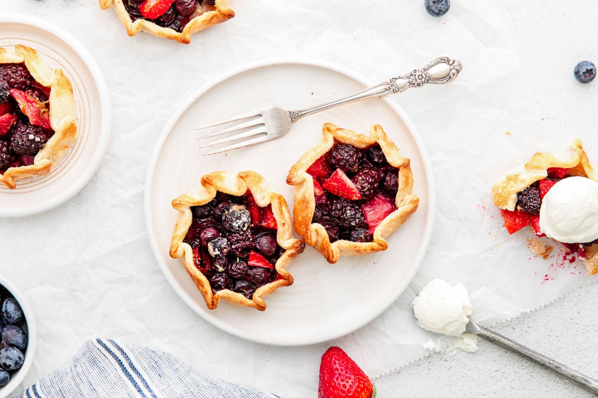 top down view of 2 mini gallettes sitting on white plate with more galettes around the plate.