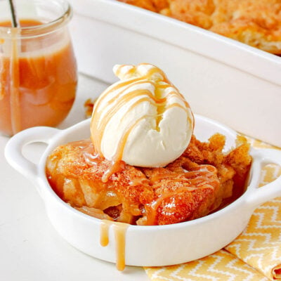 apple cobbler made with caramel sauce in small white dish topped with ice cream and salted caramel.