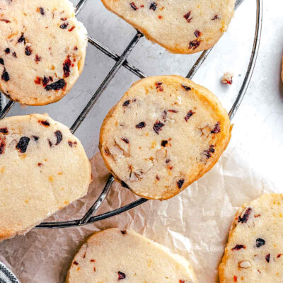 cranberry pecan shortbread cookies on a wire rack with brown parchment underneath.