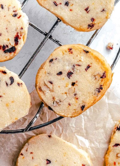cranberry pecan shortbread cookies on a wire rack with brown parchment underneath.