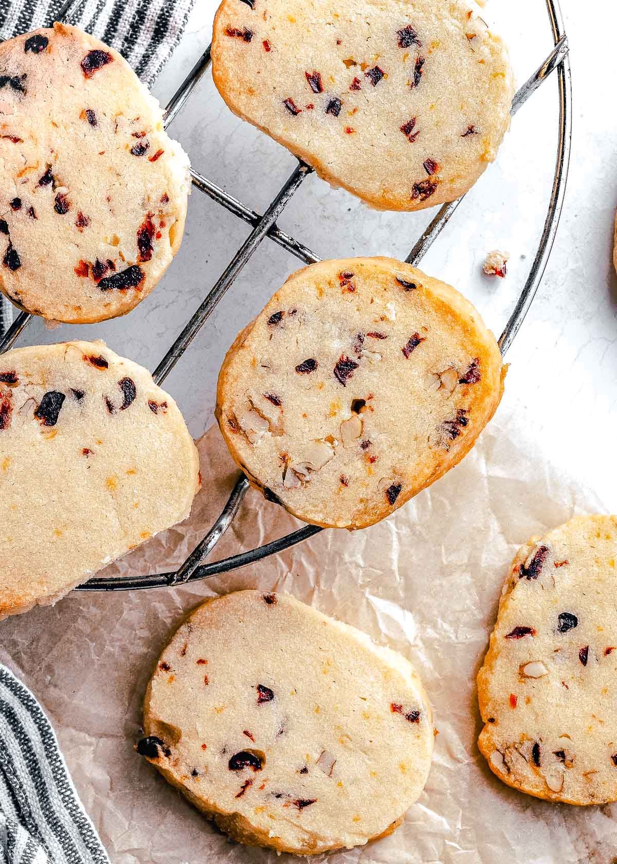 cranberry pecan shortbread cookies on a wire rack with brown parchment underneath.