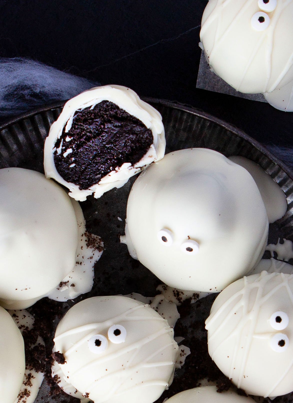 inside look at the Oreo truffle cut in half. sitting next to whole Oreo balls that are decorated and shaped as ghosts and mummies. 