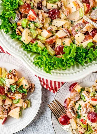 large bowl with waldorf salad in it and three small plates around the bowl that has servings of the salad on the plates.