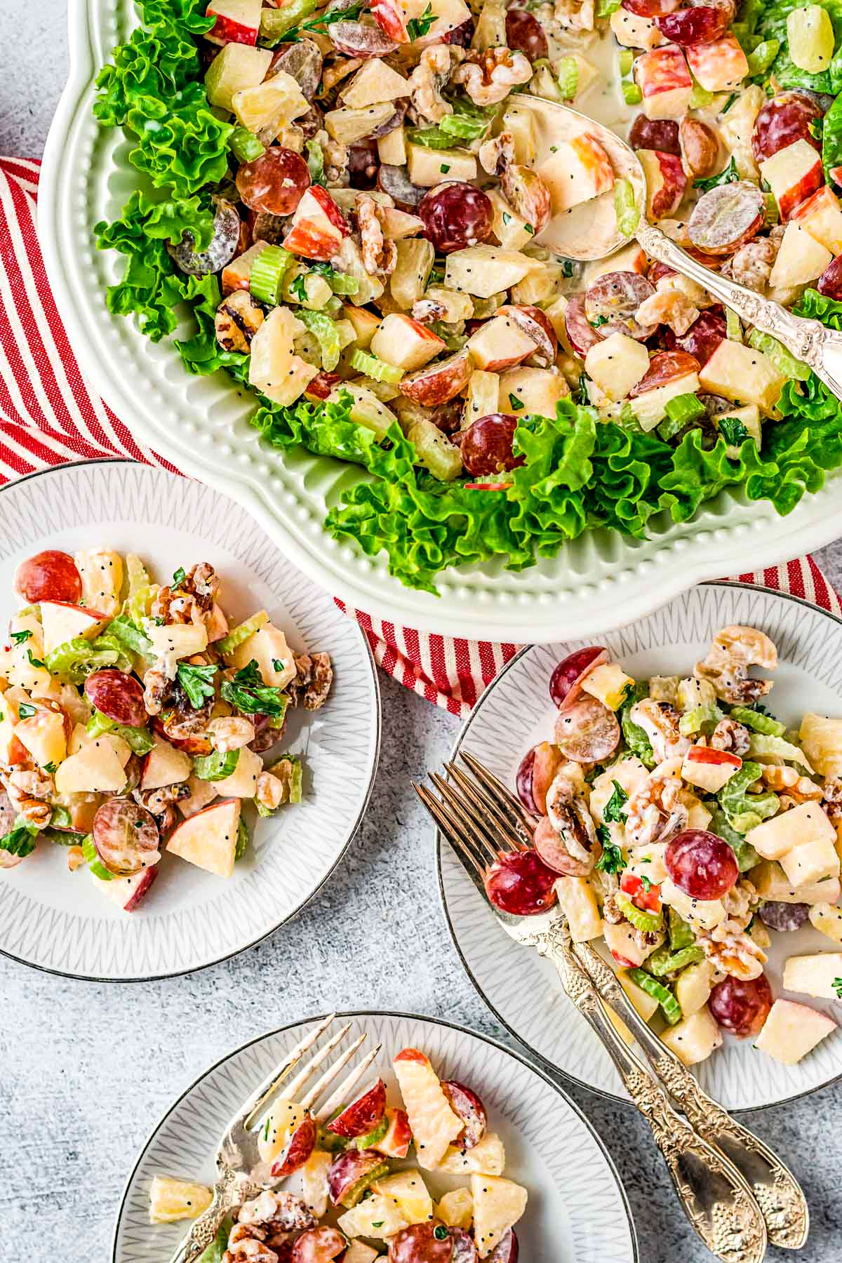 large bowl with waldorf salad in it and three small plates around the bowl that has servings of the salad on the plates.