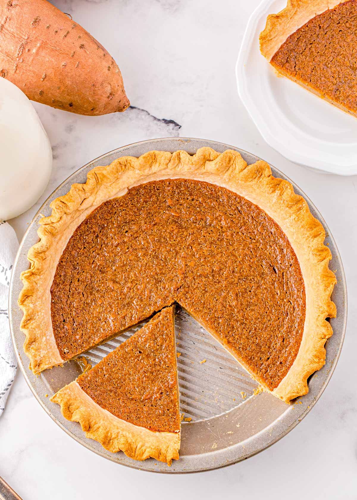 top down look at sweet potato pie with two sliced cut and one removed.