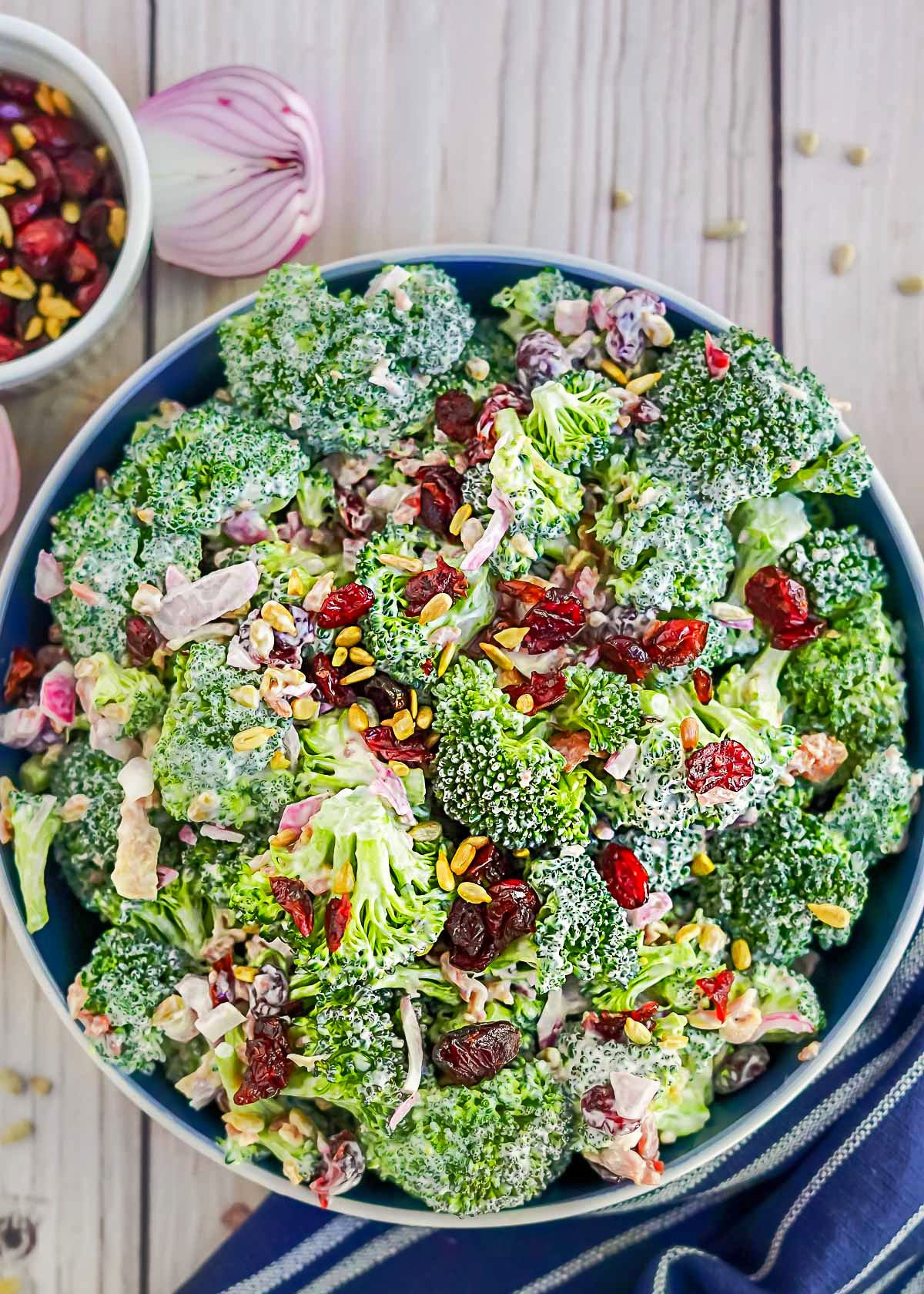 large serving bowl with freshly made broccoli salad topped with dried cranberries and bacon bits. 