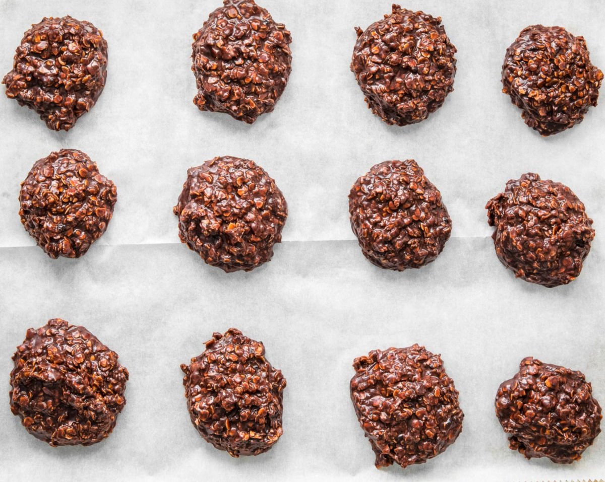 twelve no bake cookies setting up on a parchment lined baking sheet.