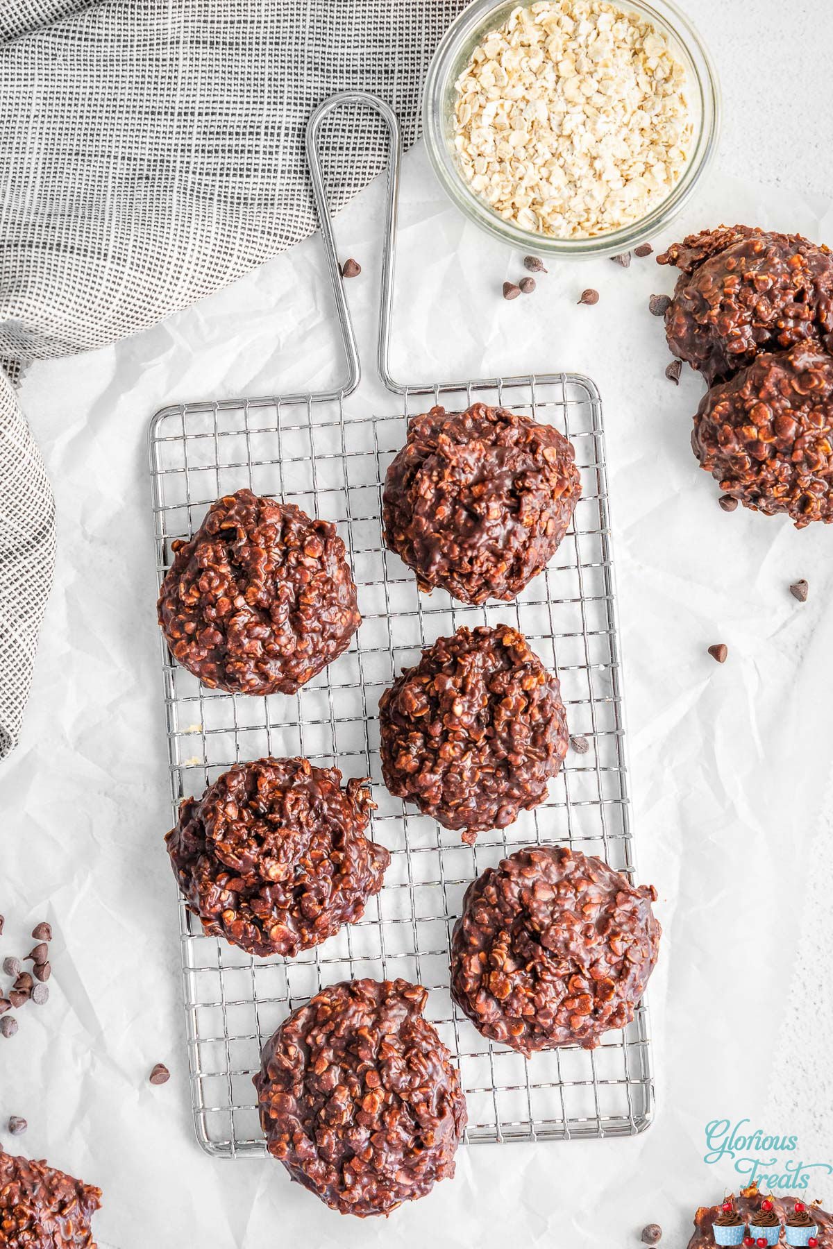 top down look at six no bake cookies on small wire cooling rack with a small bowl of oats next to it.