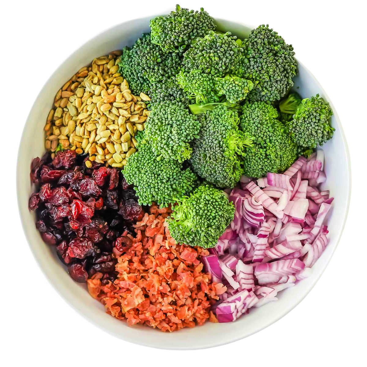 white bowl with broccoli salad ingredients in it ready to be mixed together.