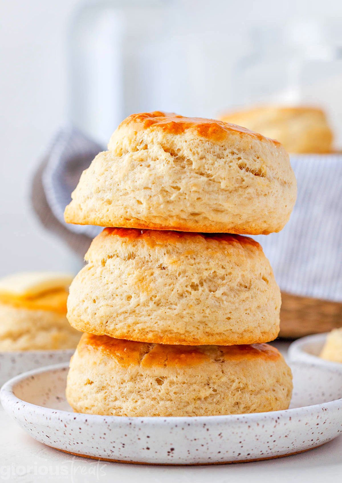 three buttermilk biscuits stacked on top of each other on a small white plate.