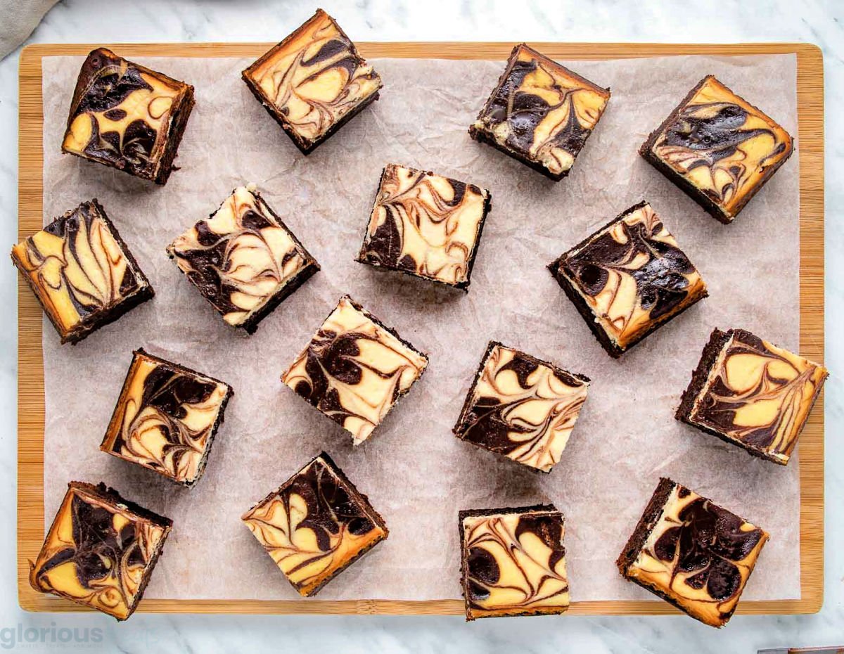 top down view of cheesecake brownies cut into small squares on a wood cutting board.