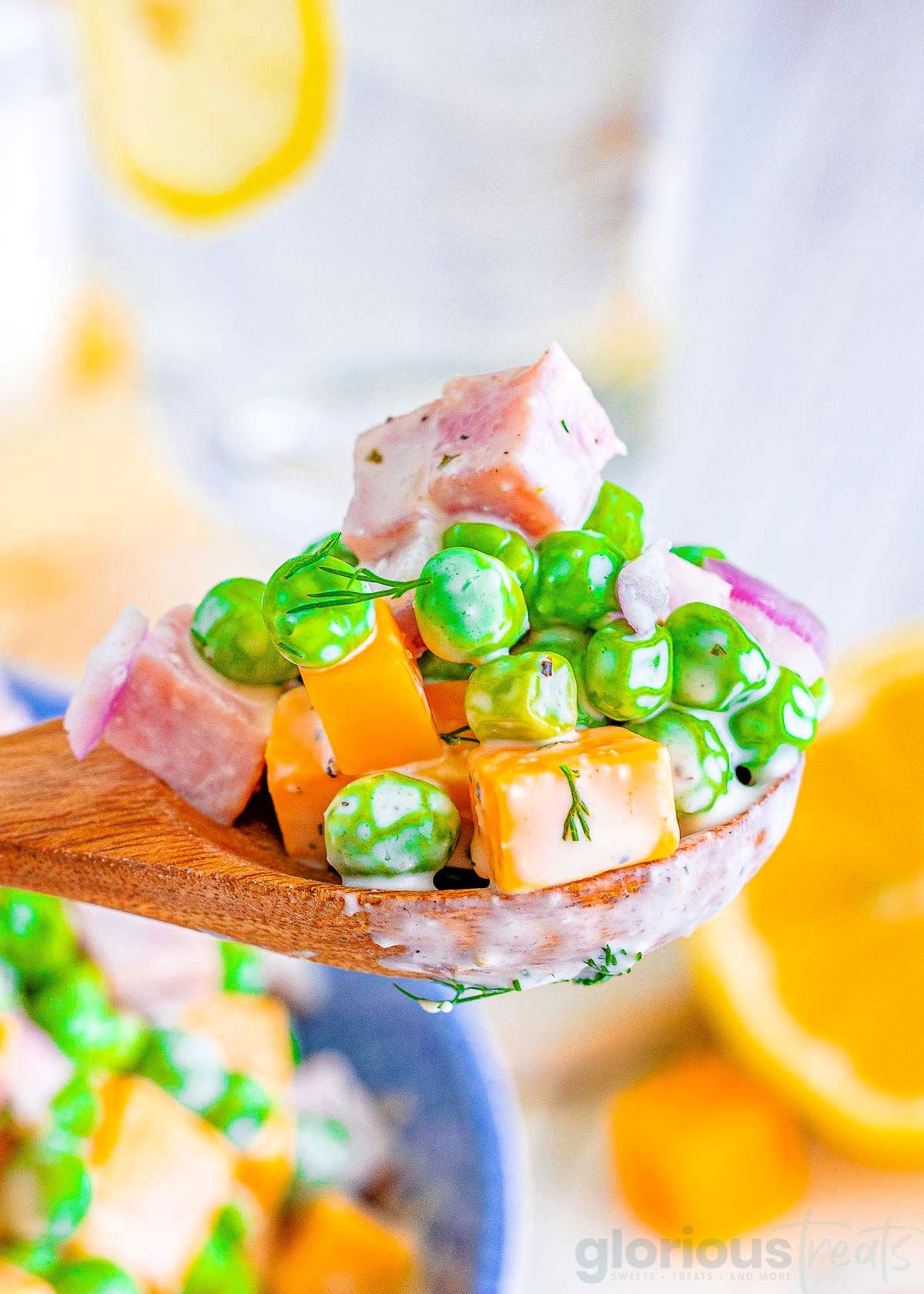 wooden spoonful of pea salad with cheese and ham.