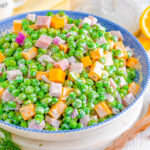 pea salad recipe made with cheddar cheese and ham in a white and blue bowl.