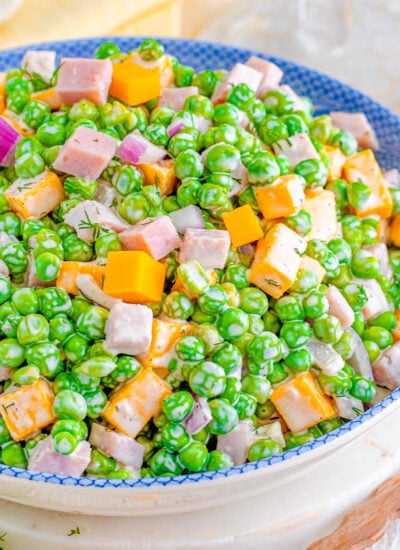 pea salad recipe made with cheddar cheese and ham in a white and blue bowl.