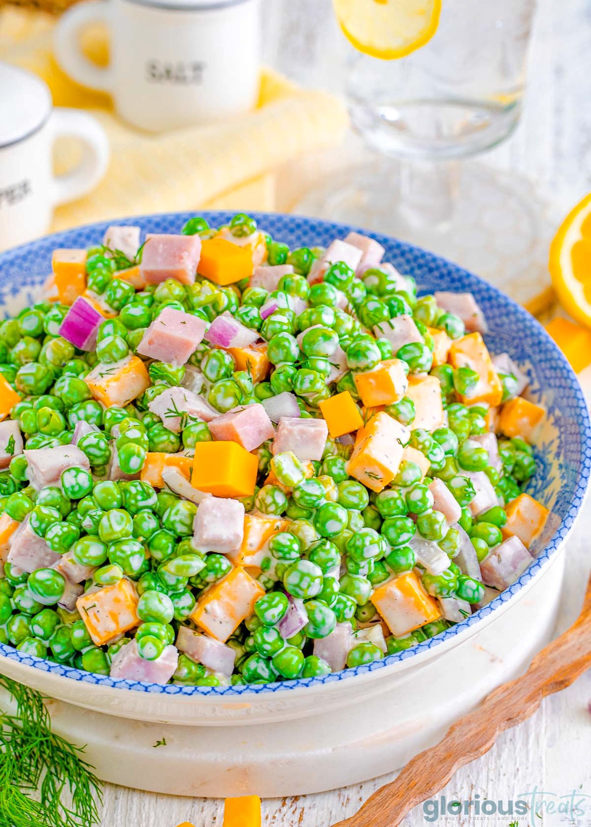 pea salad recipe made with cheddar cheese and ham in a white and blue bowl.