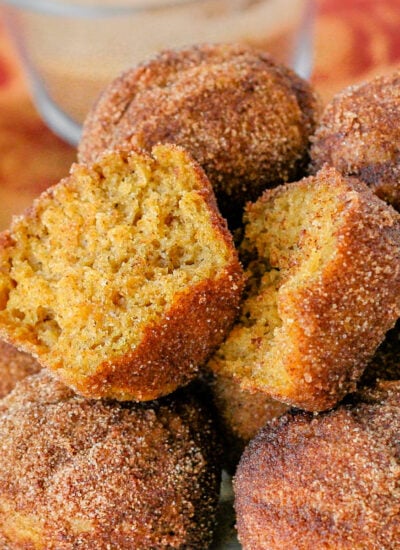 white metal pate is topped with a mound of pumpkin mini muffins rolled in cinnamon sugar so they look like donut holes. top muffin has been torn in half.