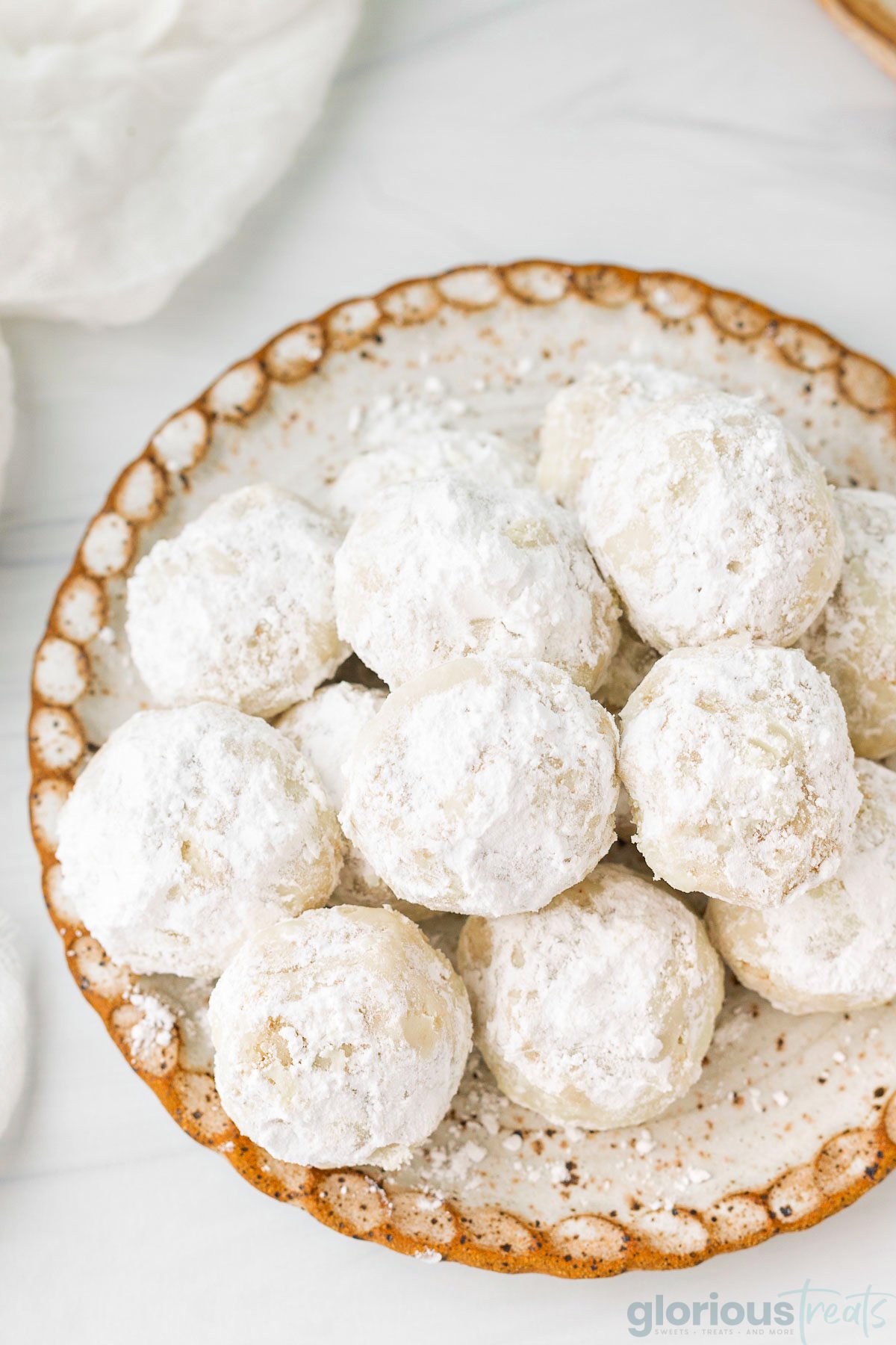 top down view of snowball cookies on white pottery plate.