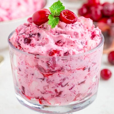 cranberry fluff dessert salad in glass individual serving cup topped with fresh cranberries and mint.