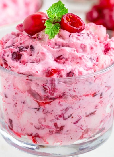 cranberry fluff dessert salad in glass individual serving cup topped with fresh cranberries and mint.