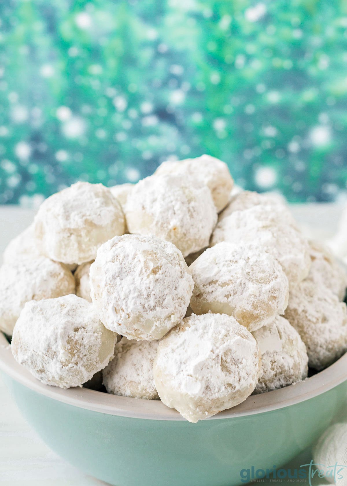 light green bowl filled with mexican wedding cookies.