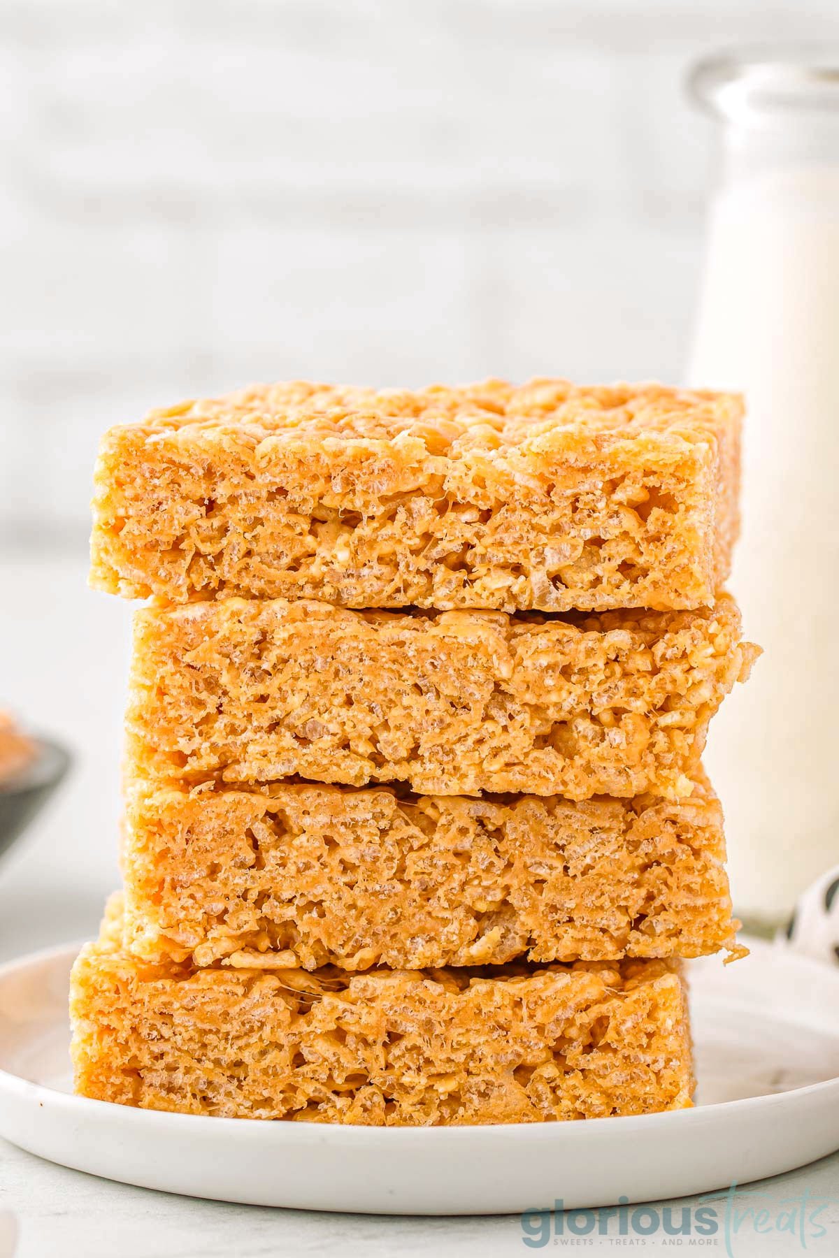 four peanut butter rice krispie treats stacked on a white round plate.