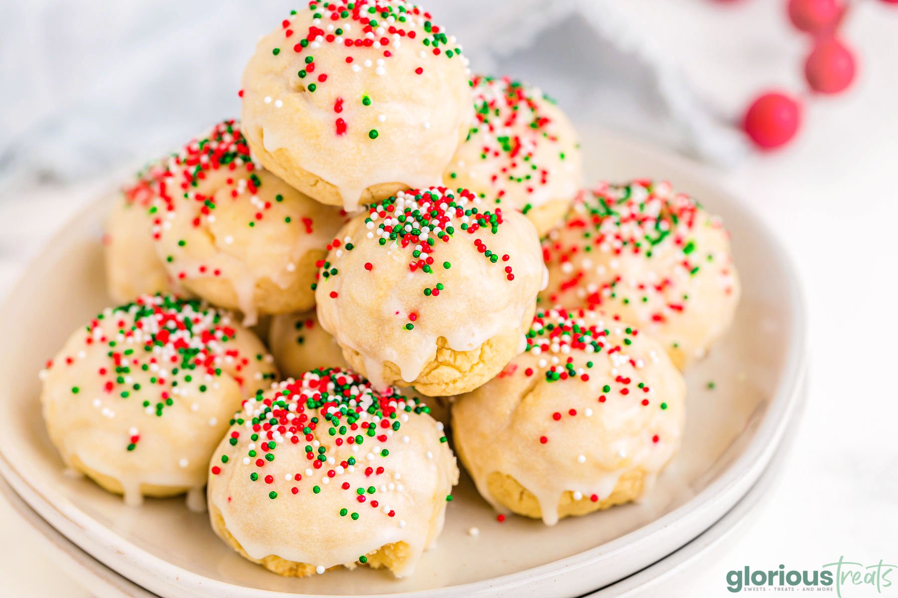 italian christmas cookies decorated with red, green and white nonpareils sitting on two white round plates.