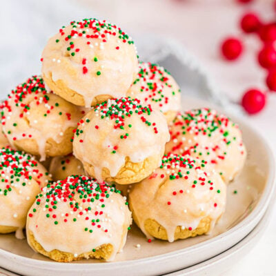 italian christmas cookies decorated with red, green and white nonpareils sitting on two white round plates.